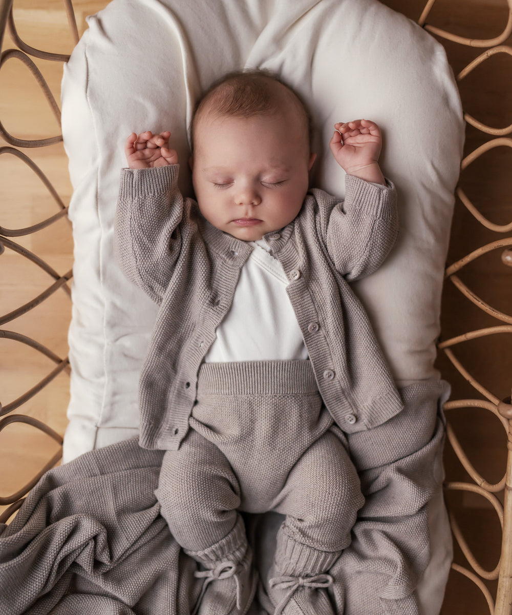 Baby med beige strikket babytæppe