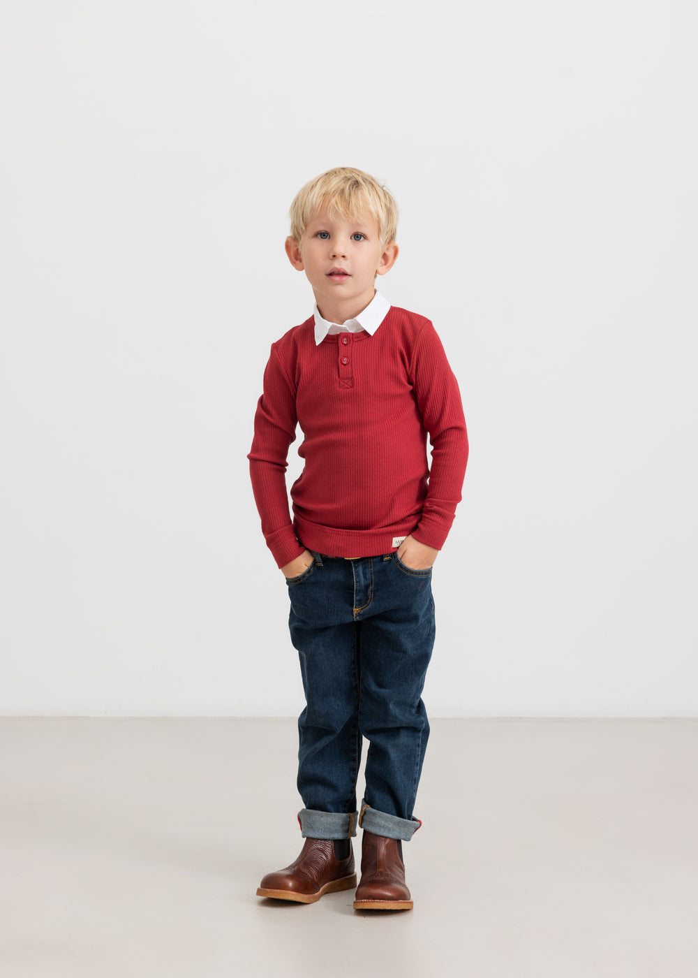 Dreng iført rød ribbluse, hvid skjorte og mørke børnejeans