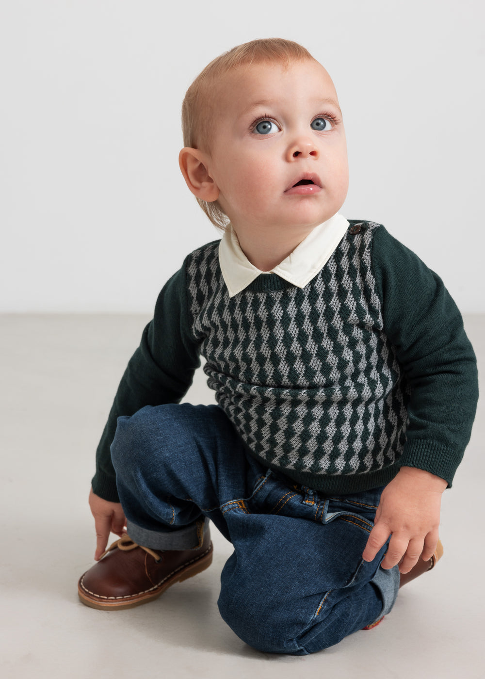 Baby iført mørkegrøn ternet strikbluse med skjortekrave og jeans