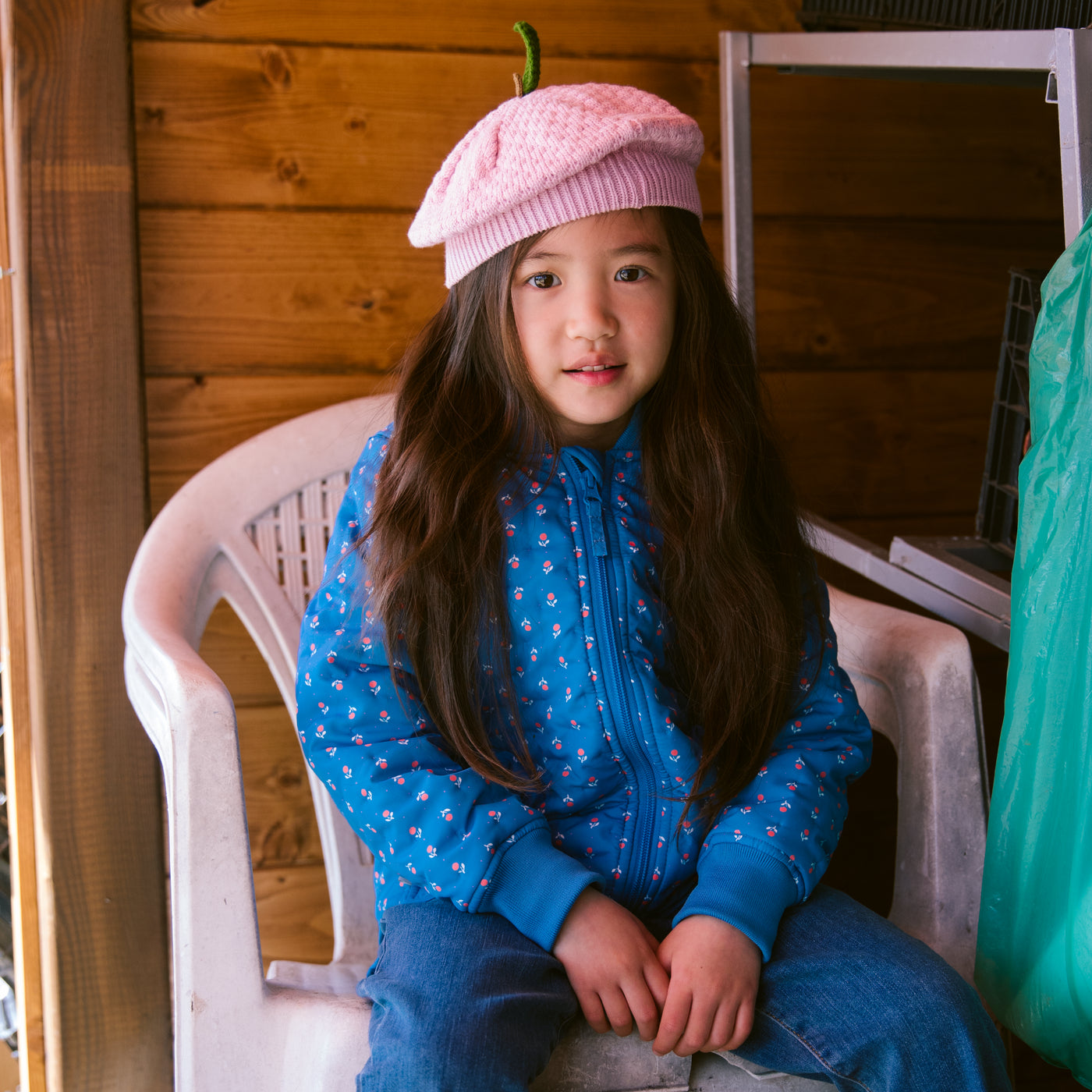 Barn iført blå jakke med små blomster og lyserød strikket baret