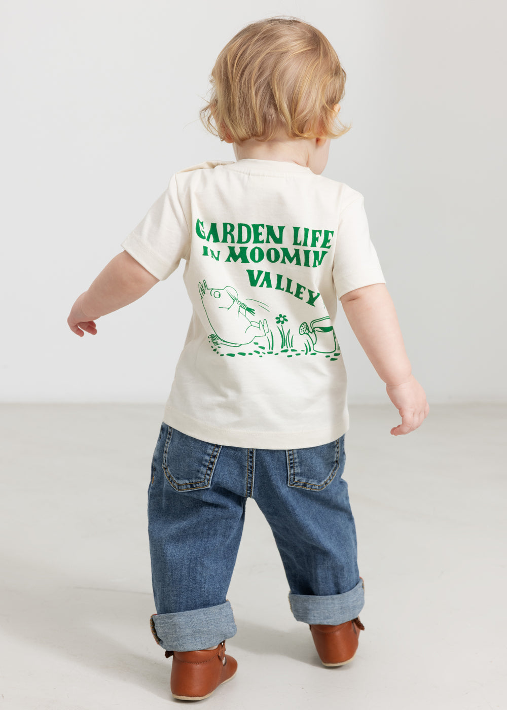Baby iført råhvid T-shirt med grønt Moomin print og jeans