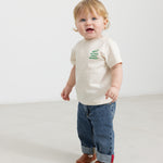 Baby iført råhvid T-shirt med grønt Moomin print og jeans