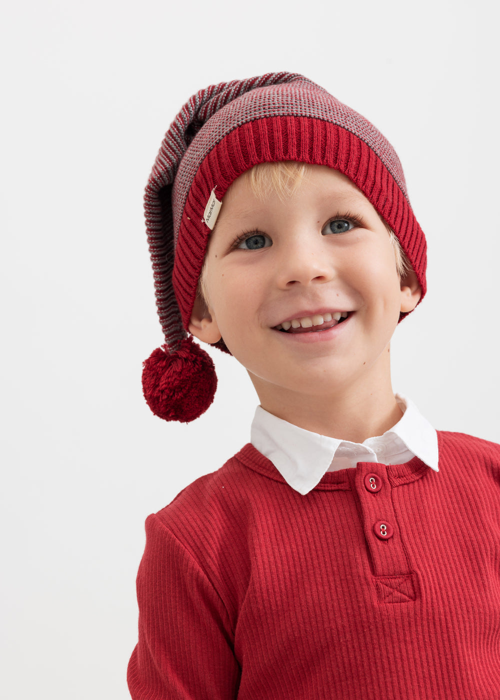 Dreng iført strikket nissehue med røde og grå striber og rød trøje til børn