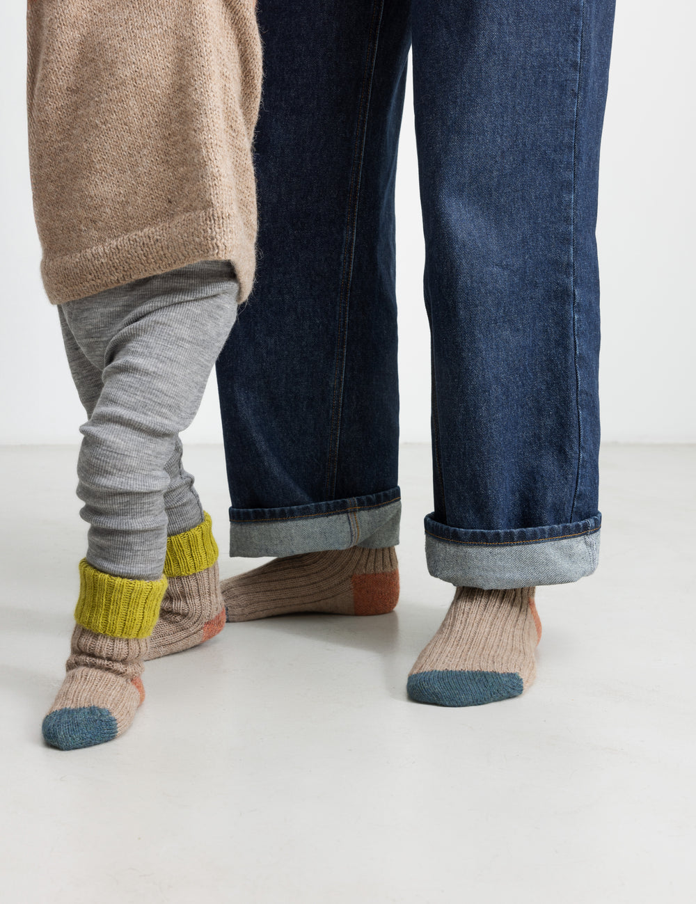 Børn iført uldstriksokker i beige med grøn ribbe