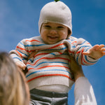 Baby iført strikket hue og stribet bluse