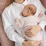 Rosa melerede strikkede babysko på babyfødder, med snørebånd