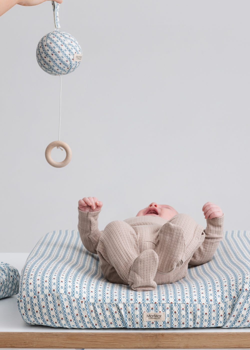 Børn iført beige pointelle heldragt på puslebord