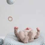 Børn iført beige pointelle heldragt på puslebord