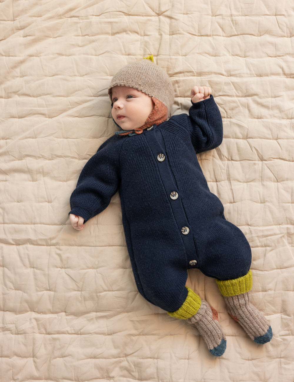 Baby og uldstriksokker ligger på tæppe