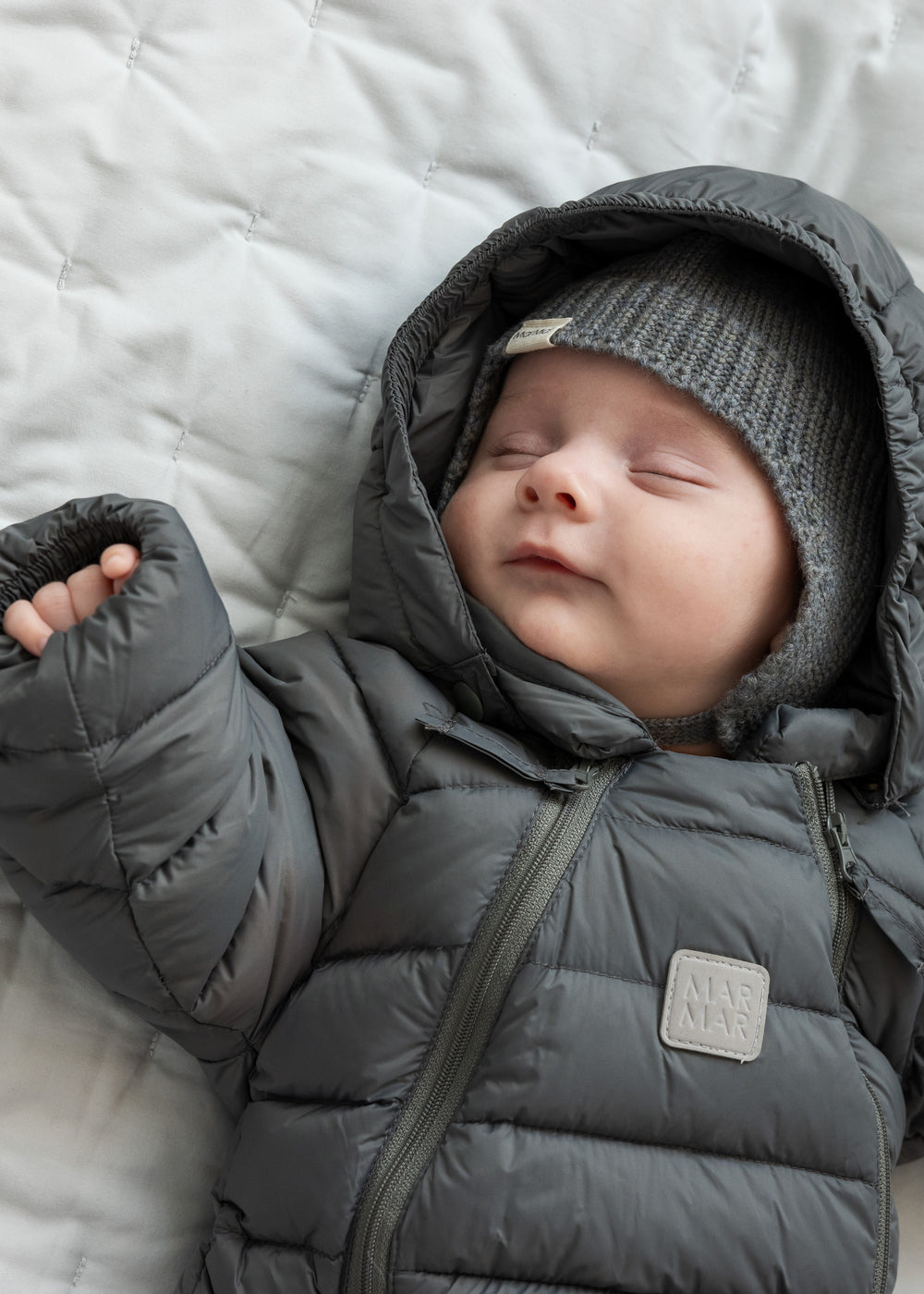 Sovende baby i mørkegrå dundragt med hætte og hue