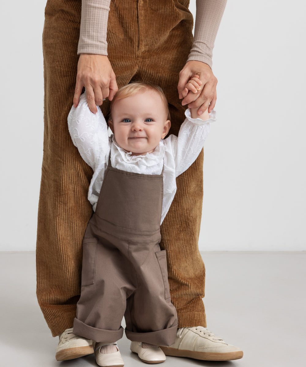 barn iført brune selebukser og hvid bluse