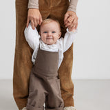 barn iført brune selebukser og hvid bluse