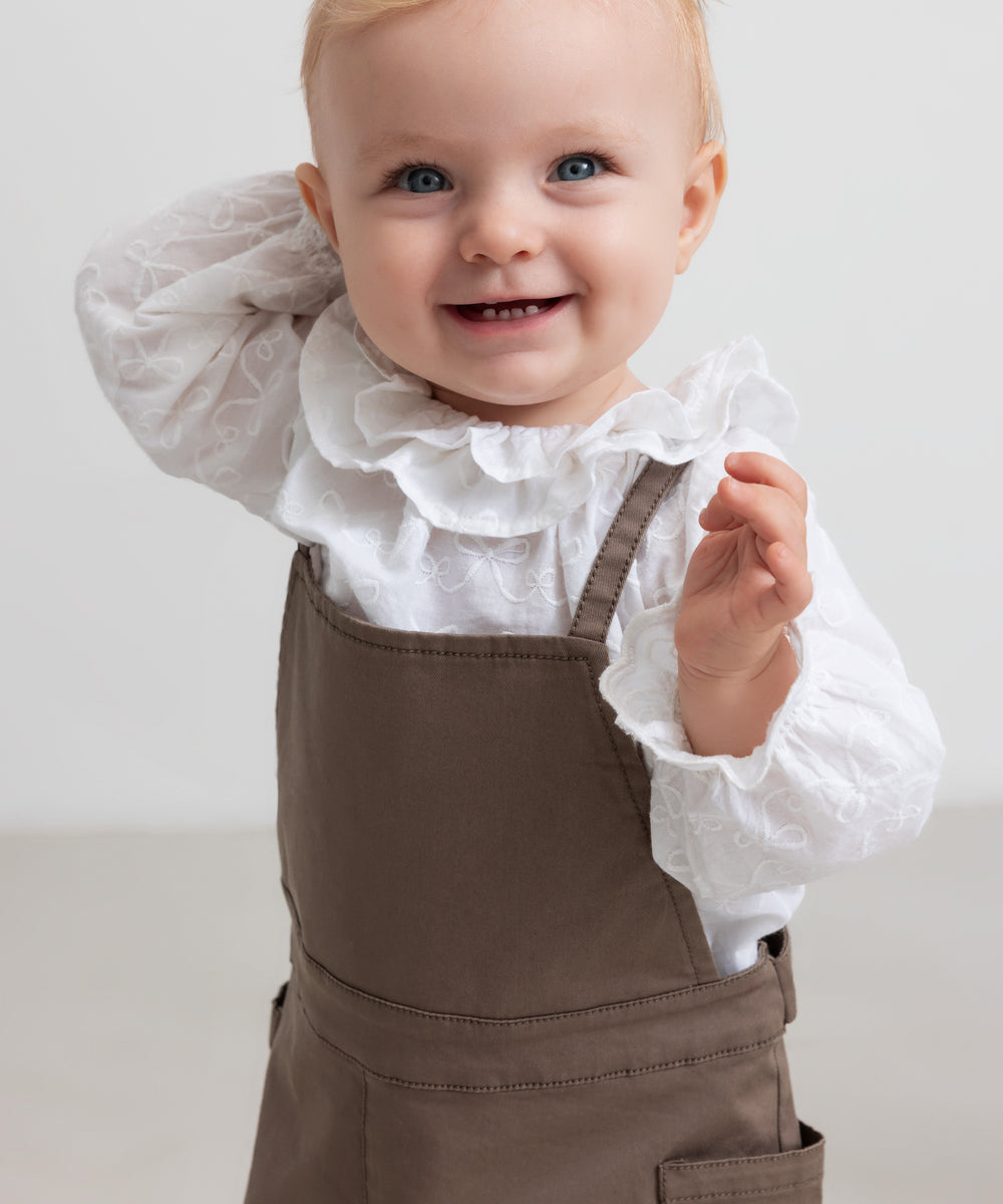 barn iført brune selebukser og hvid bluse