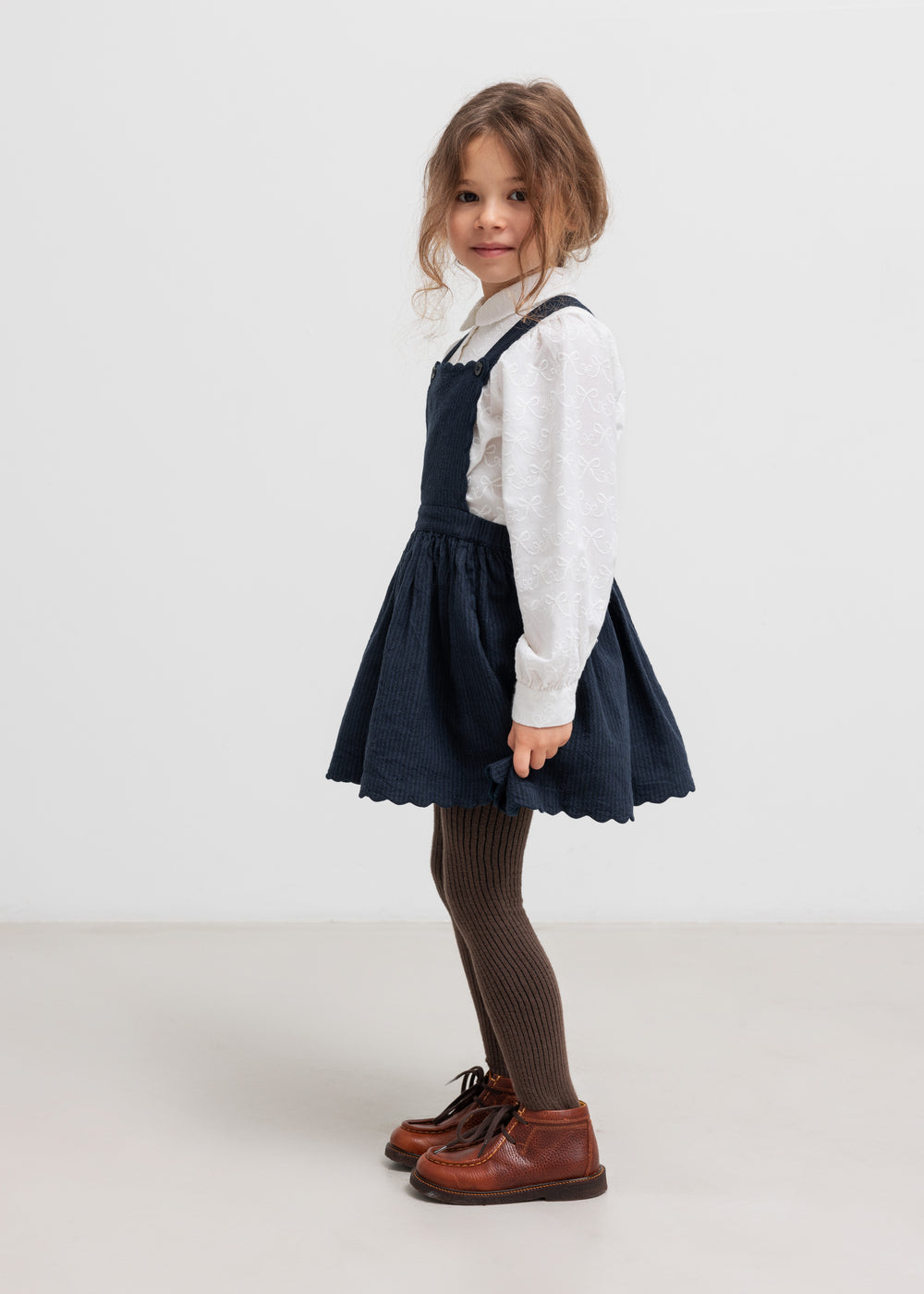 Pige iført mørkeblå selekjole og hvid bluse