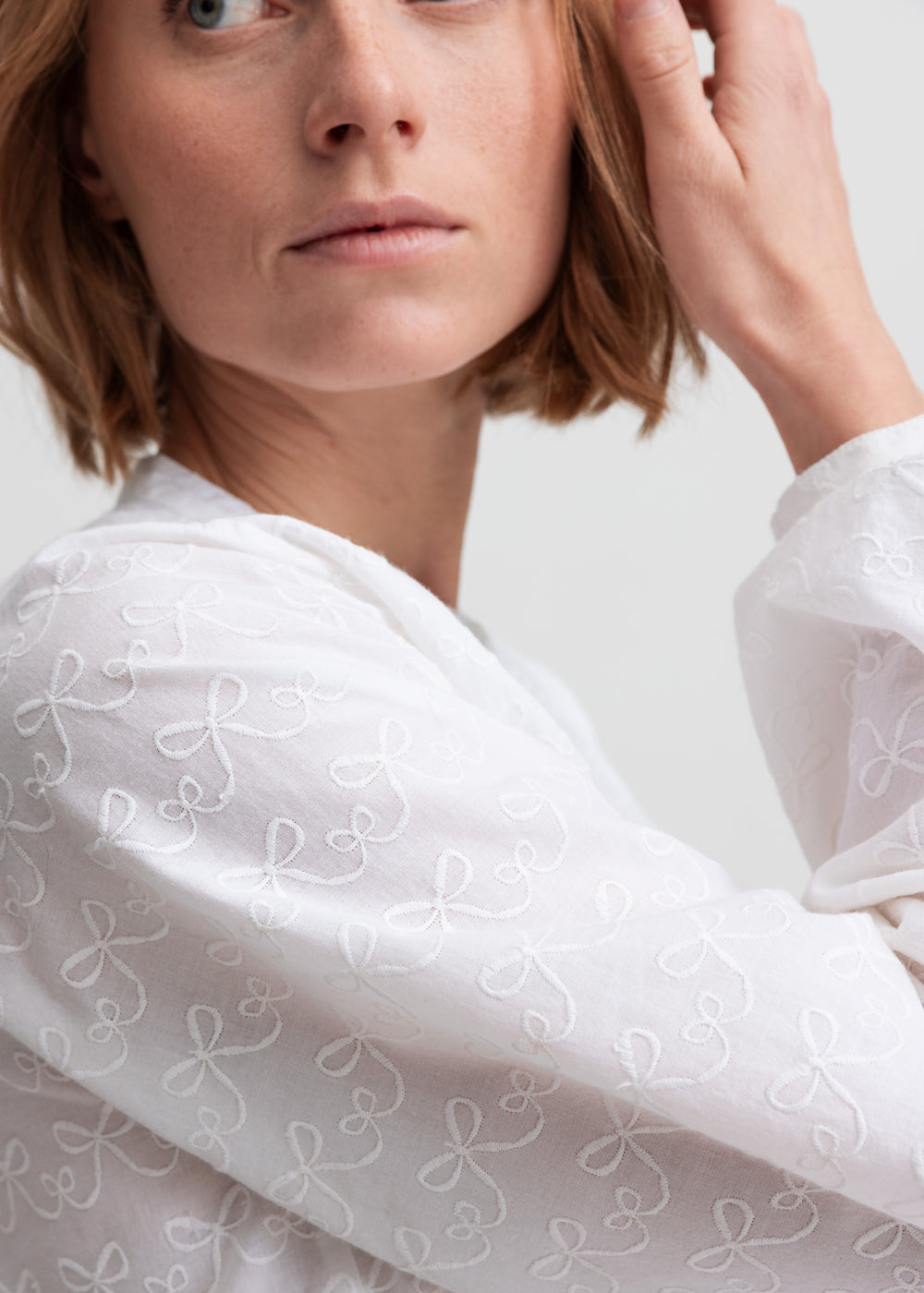 Kvinde iført hvid skjortebluse med broderet mønster