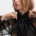 Kvinde iført sort gennemsigtig tylbluse med stor sløjfe