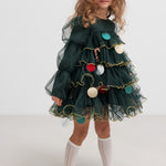 Pige iført mørkegrøn julekjole i tyl med guldkanter og juledetaljer til børn