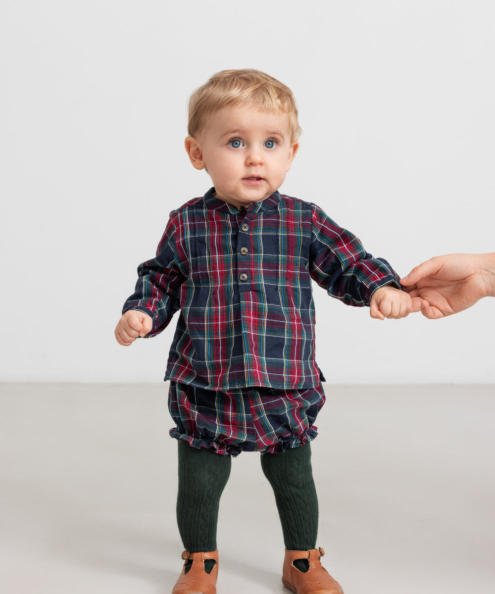 Baby iført mørkeblå og rød ternede bloomers og matchende juleskjorte