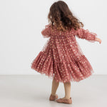 Pige iført rosa festkjole i tyl med guldprint og flæser til børn