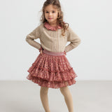 Pige iført støvet rosa bluse, glimmercardigan og lyserød festnederdel i tyl