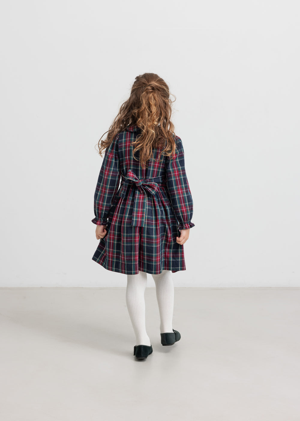 Pige iført ternet julekjole og cremefarvede strømpebukser til børn