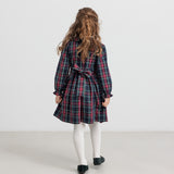 Pige iført ternet julekjole og cremefarvede strømpebukser til børn