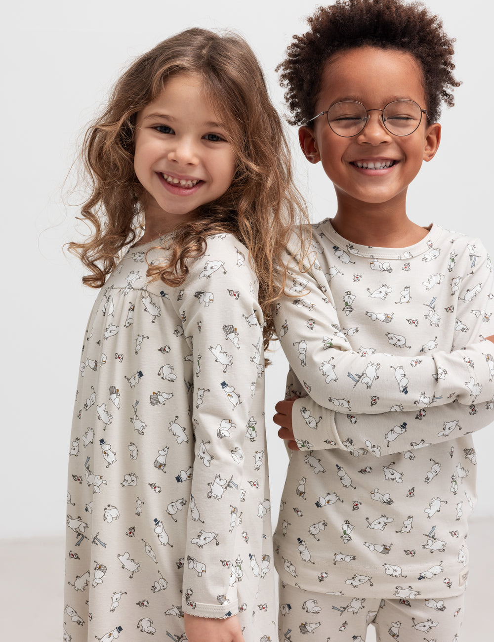 Til glade børn iført nattøj med Moomin-print, stående sammen