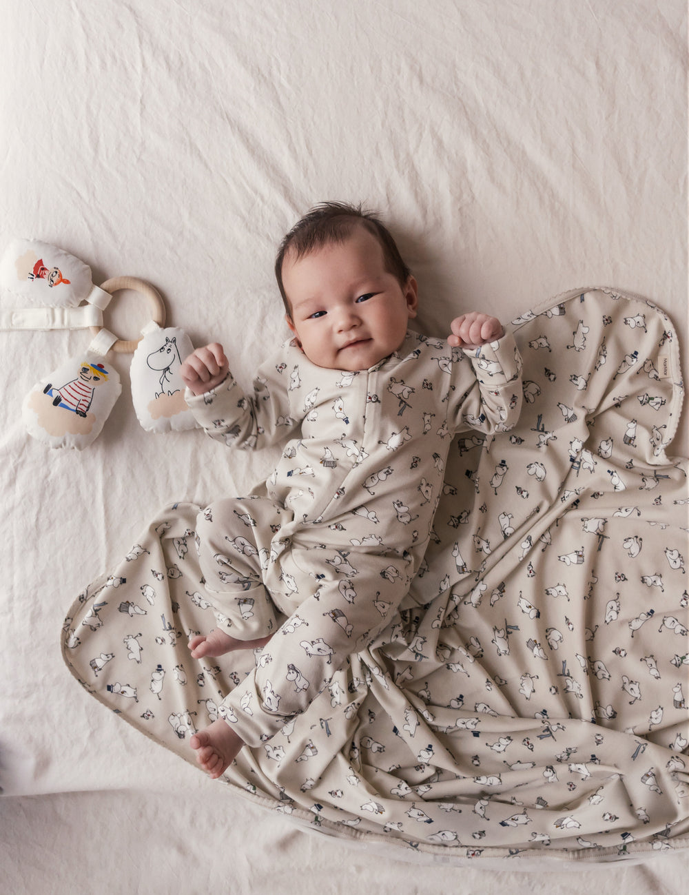 Baby ligger på baby tæppe med Moomin-print.