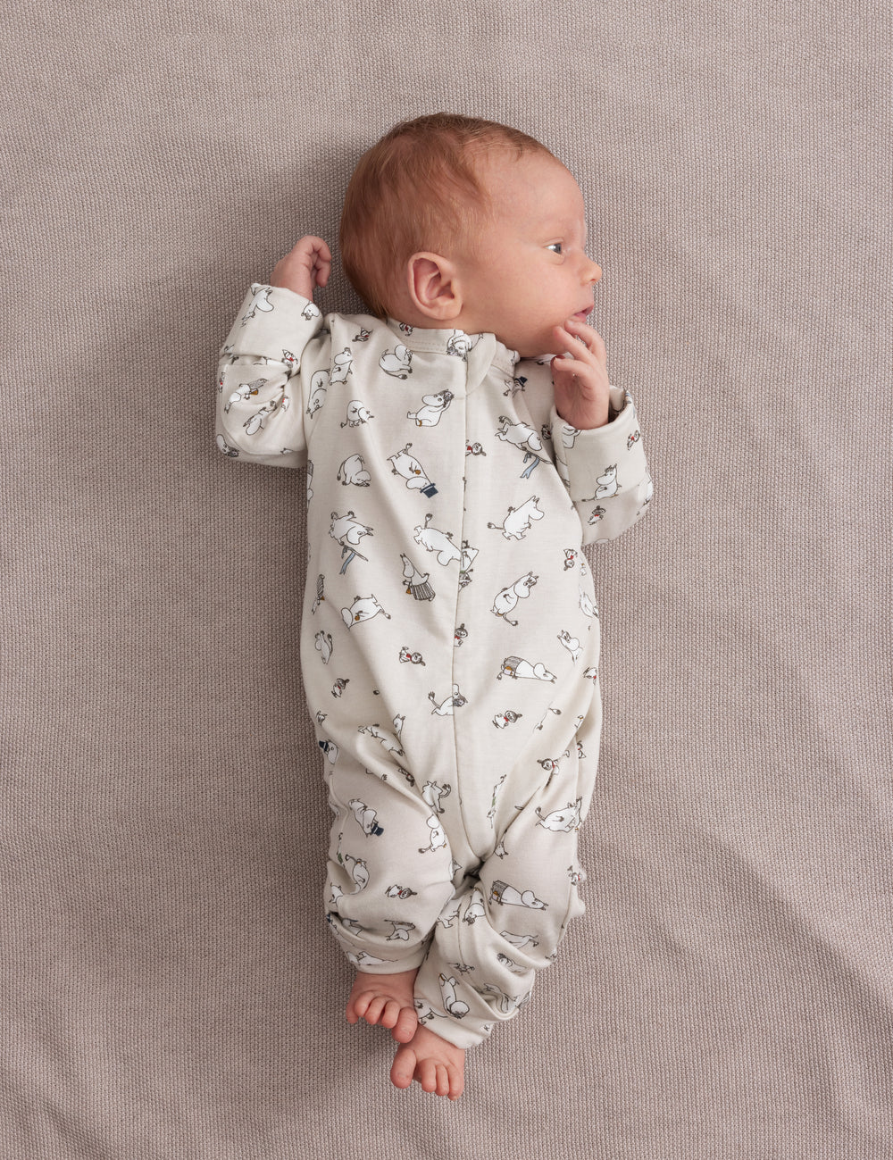 Baby iført lys holdragt med Moomin-mønster