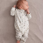 Baby iført lys heldragt med Moomin-mønster