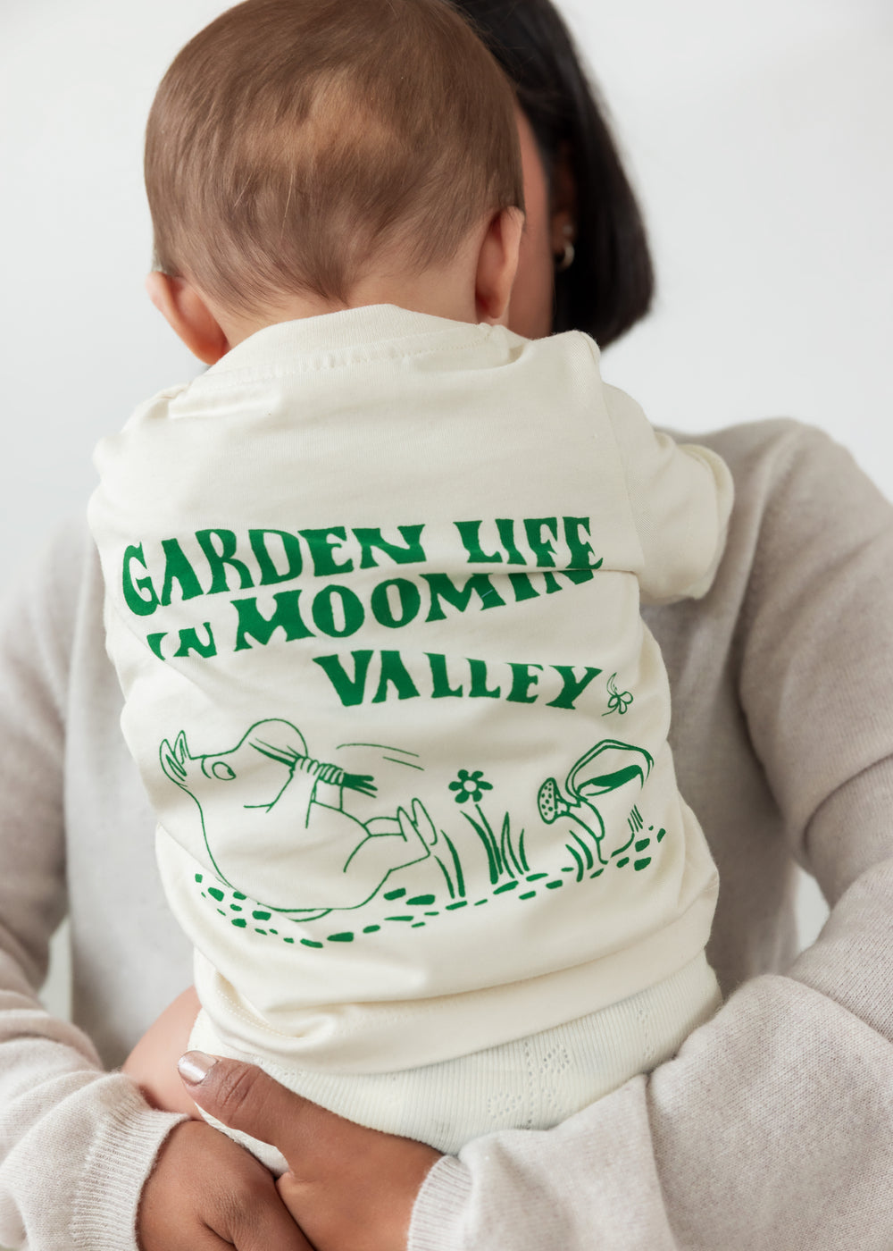 Baby iført råhvid t-shirt med grønt Moomin print