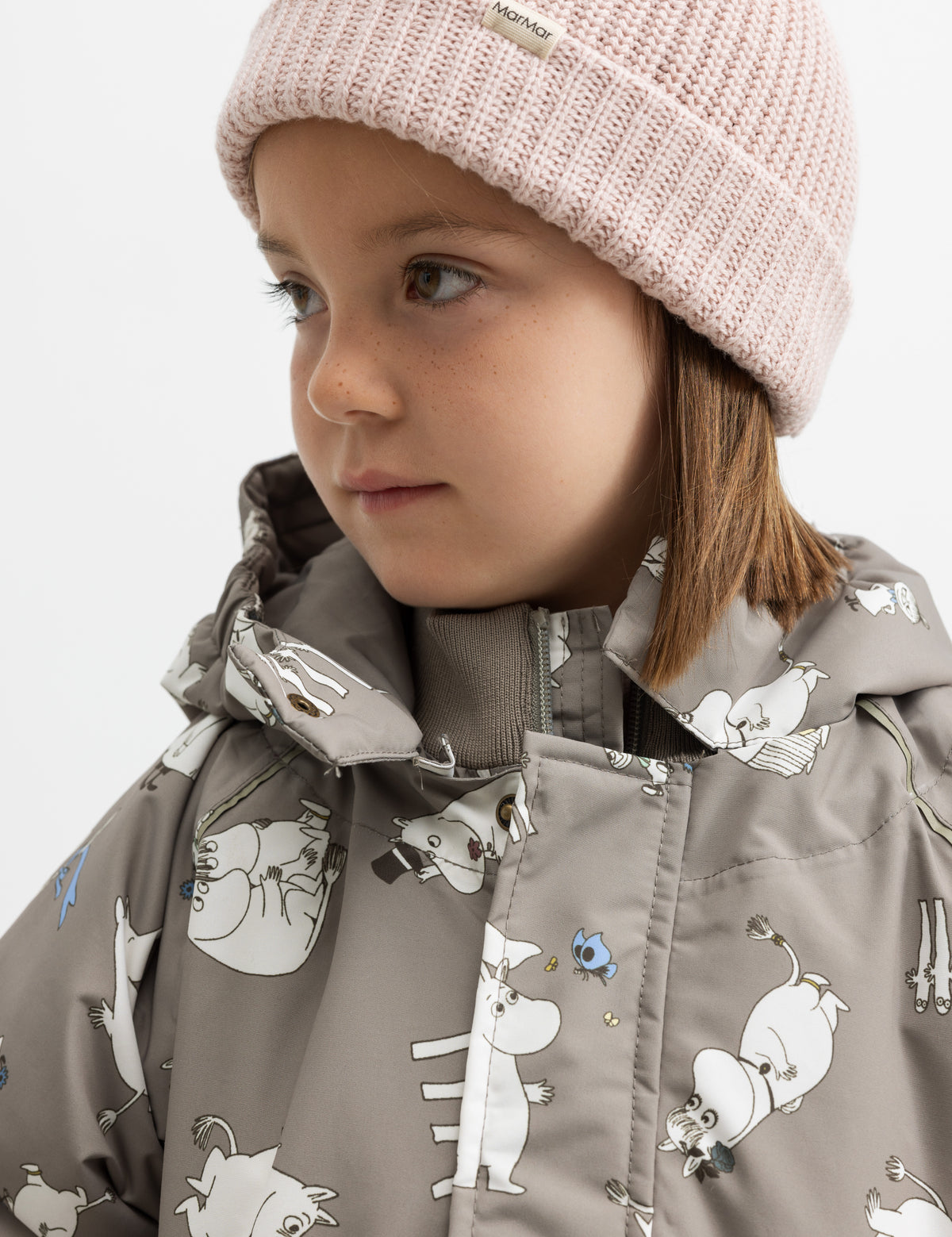 Barn i jakke med Moomin print og lyserød strikhue