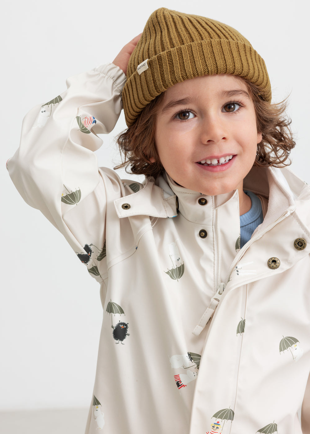 Barn iført beige regnjakke med Moomin print og strikket hue