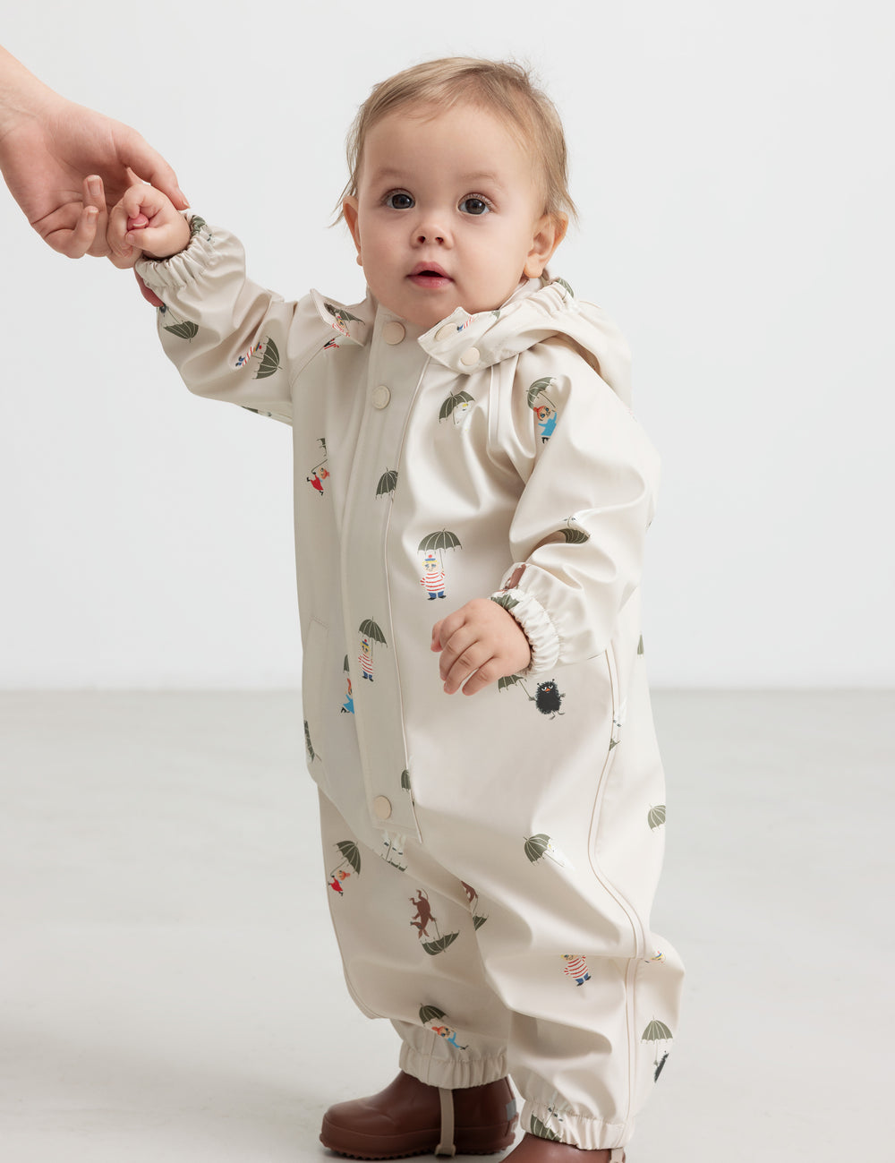 Baby iført beige regndragt med Moomin print og hætte