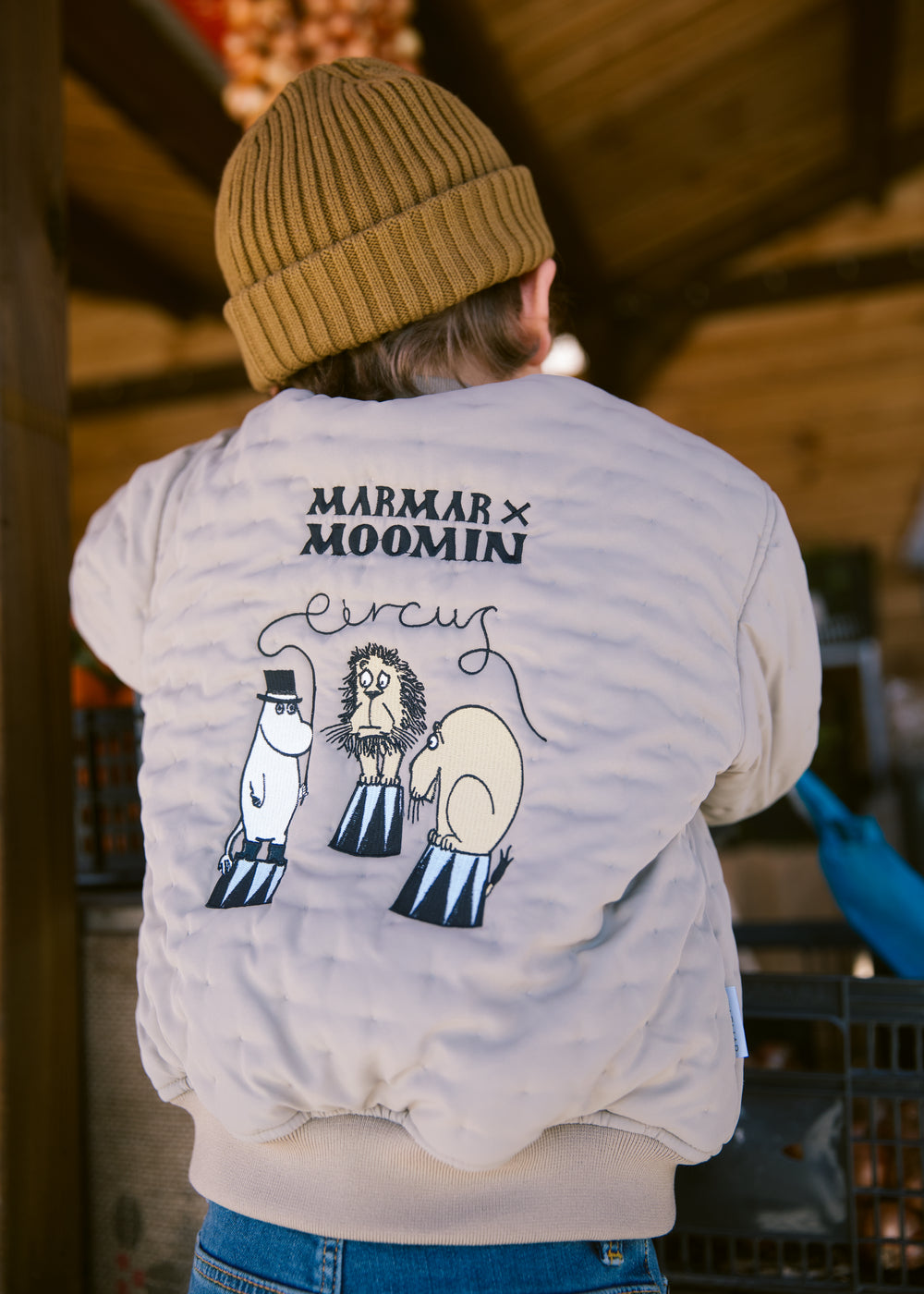 Barn set bagfra iført brun strikket hue og jakke med Moomin print