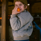 Barn i grøn Moomin jakke holdende frugt i