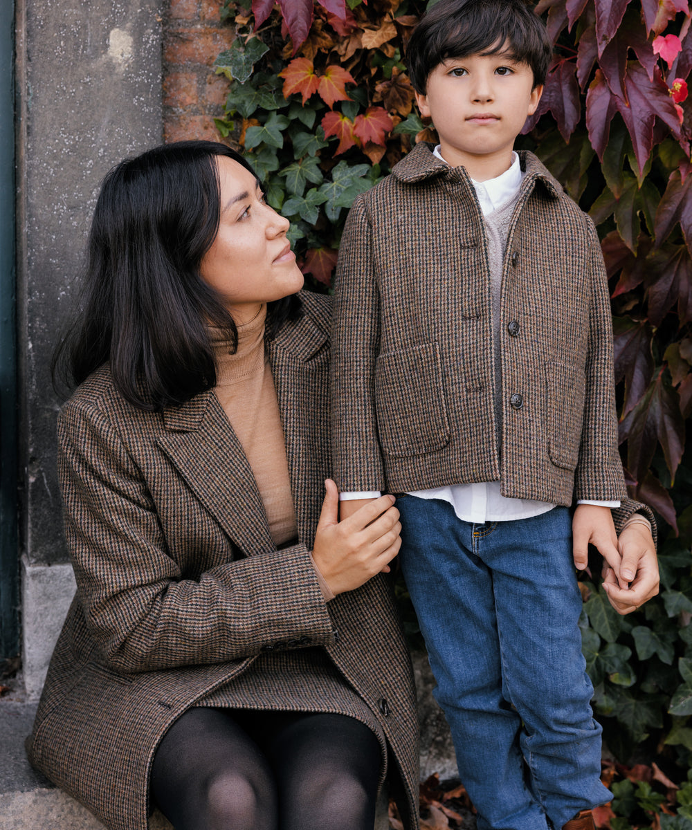 Kvinde i brun blazer sammen med barn i ternet jakke