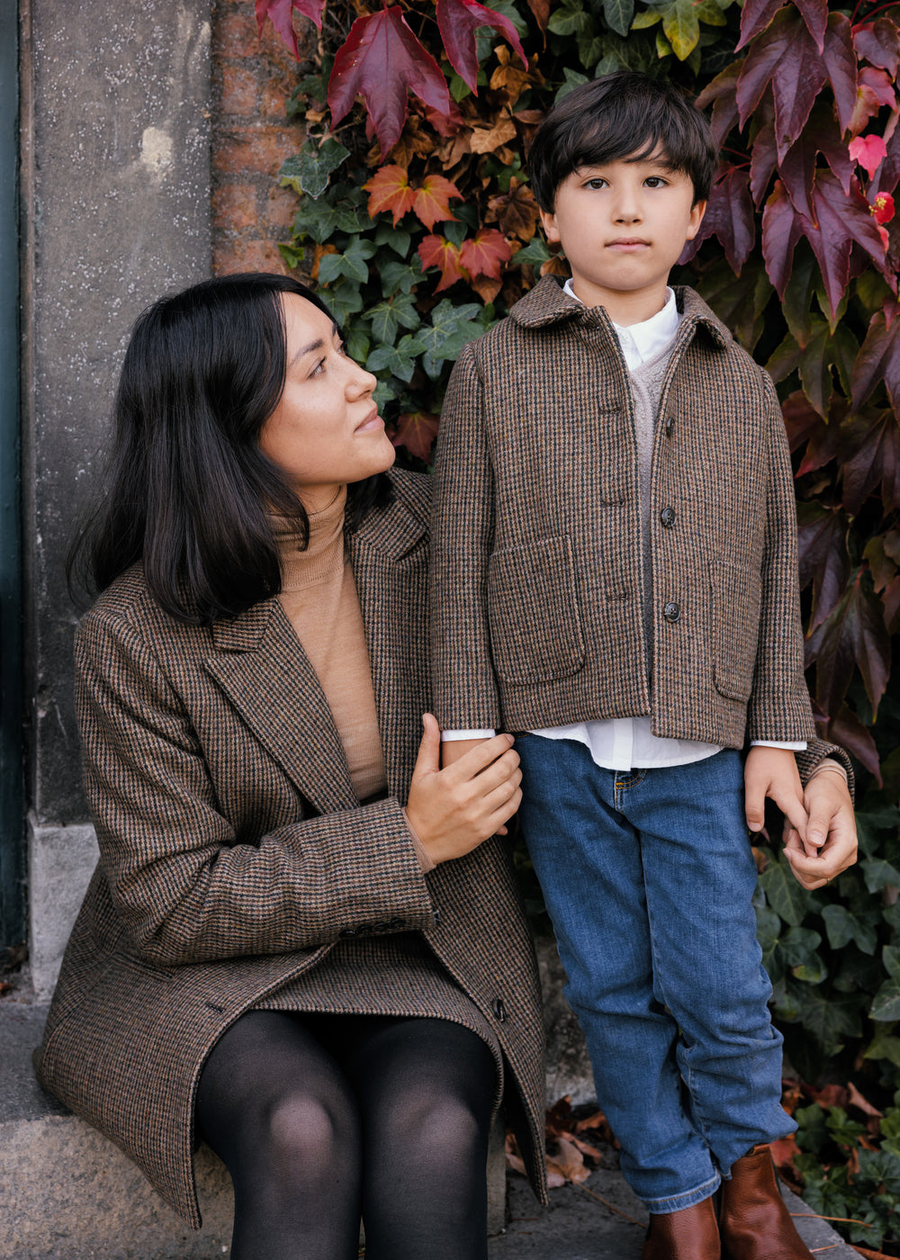 Kvinde i brun blazer sammen med barn i ternet jakke