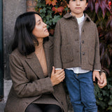 Kvinde i brun blazer sammen med barn i ternet jakke