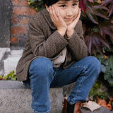 Barn i brun ternet jakke sidder på trappe