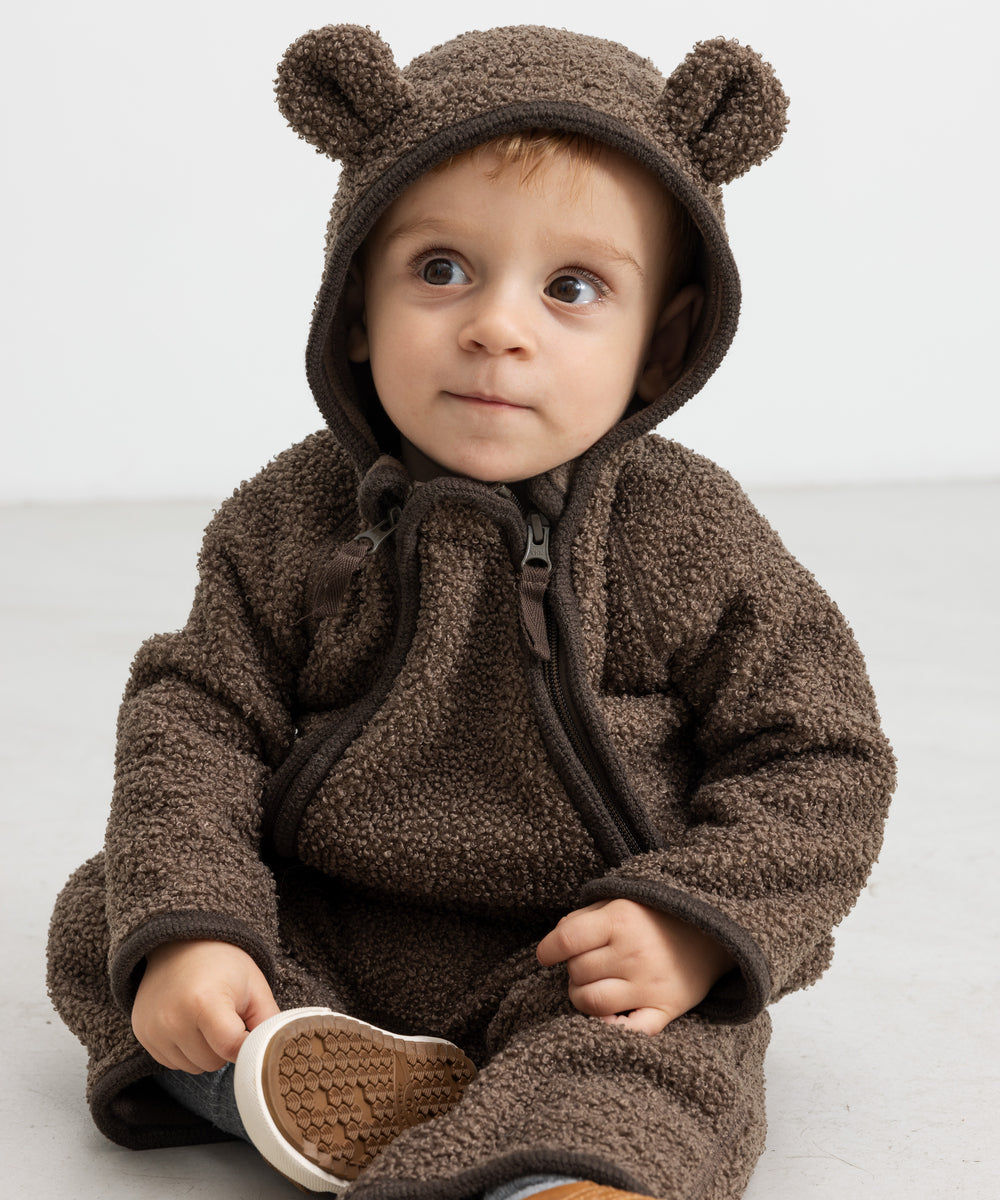 Baby i brun heldragt med ører, sidder og kigger op