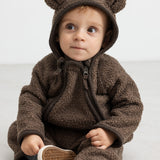 Baby i brun heldragt med ører, sidder og kigger op