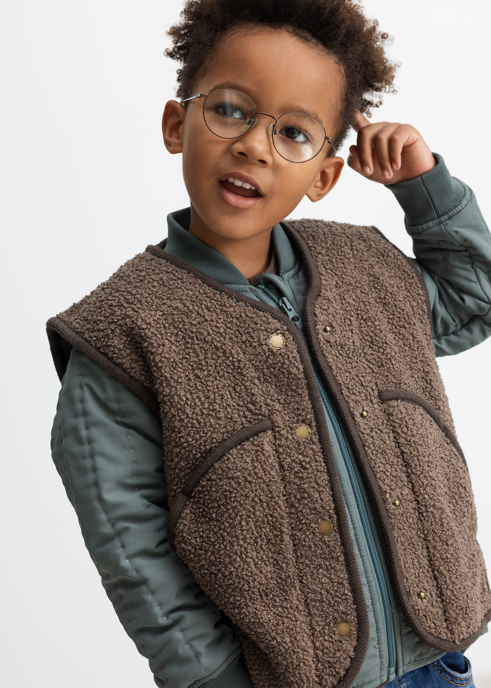 Barn iført brun teddyvest over jakke 