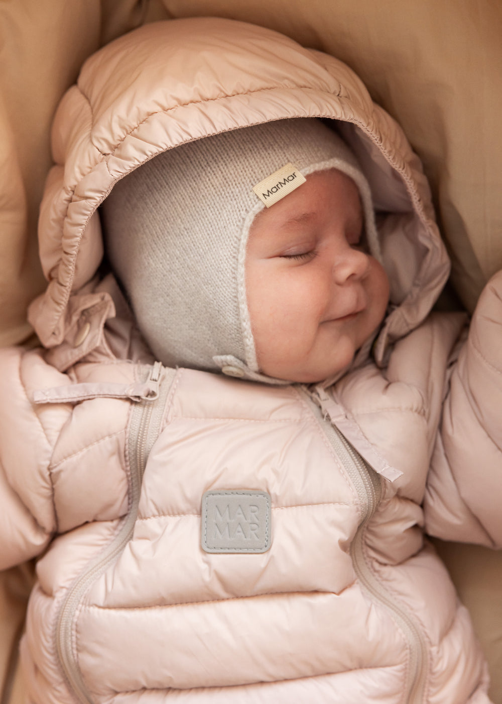 Baby iført lyserød dundragt og strikket hue