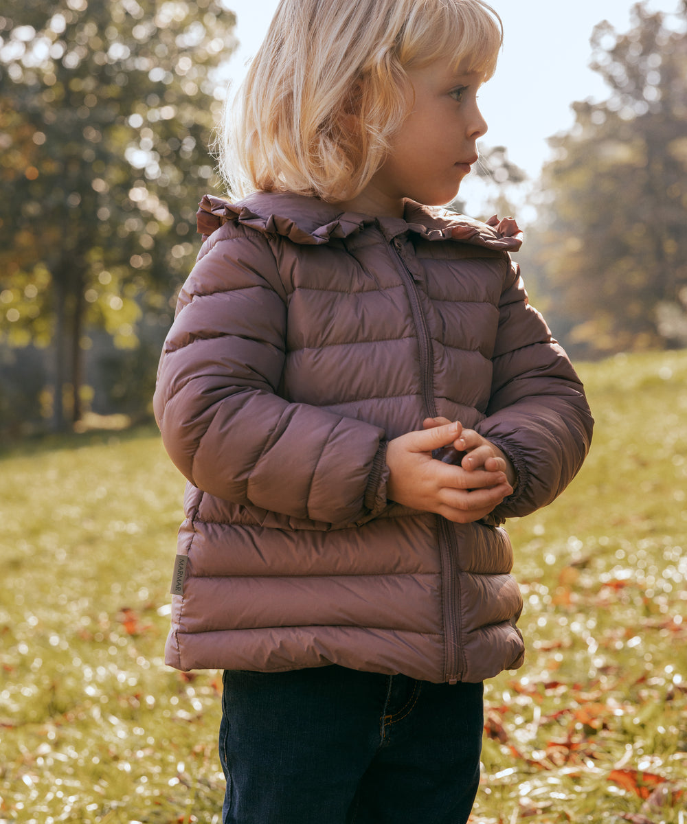 Børn leger i efterårsblade iført rosa vatteret jakke med flæsekrave