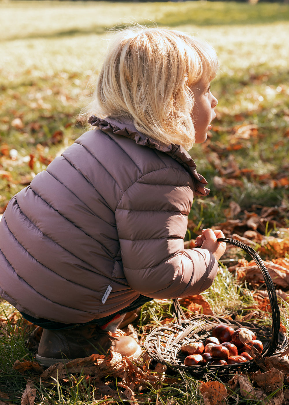 Børn bøjer sig ned iført rosa vatteret jakke med flæsekrave i naturen