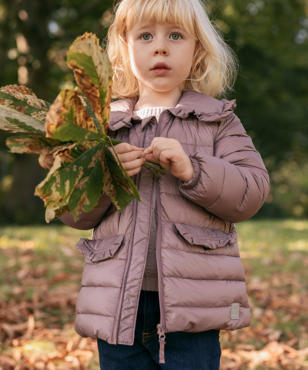 Pige i naturen iført rosa vatteret jakke med krave