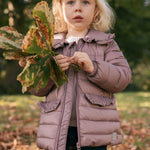 Pige i naturen iført rosa vatteret jakke med krave
