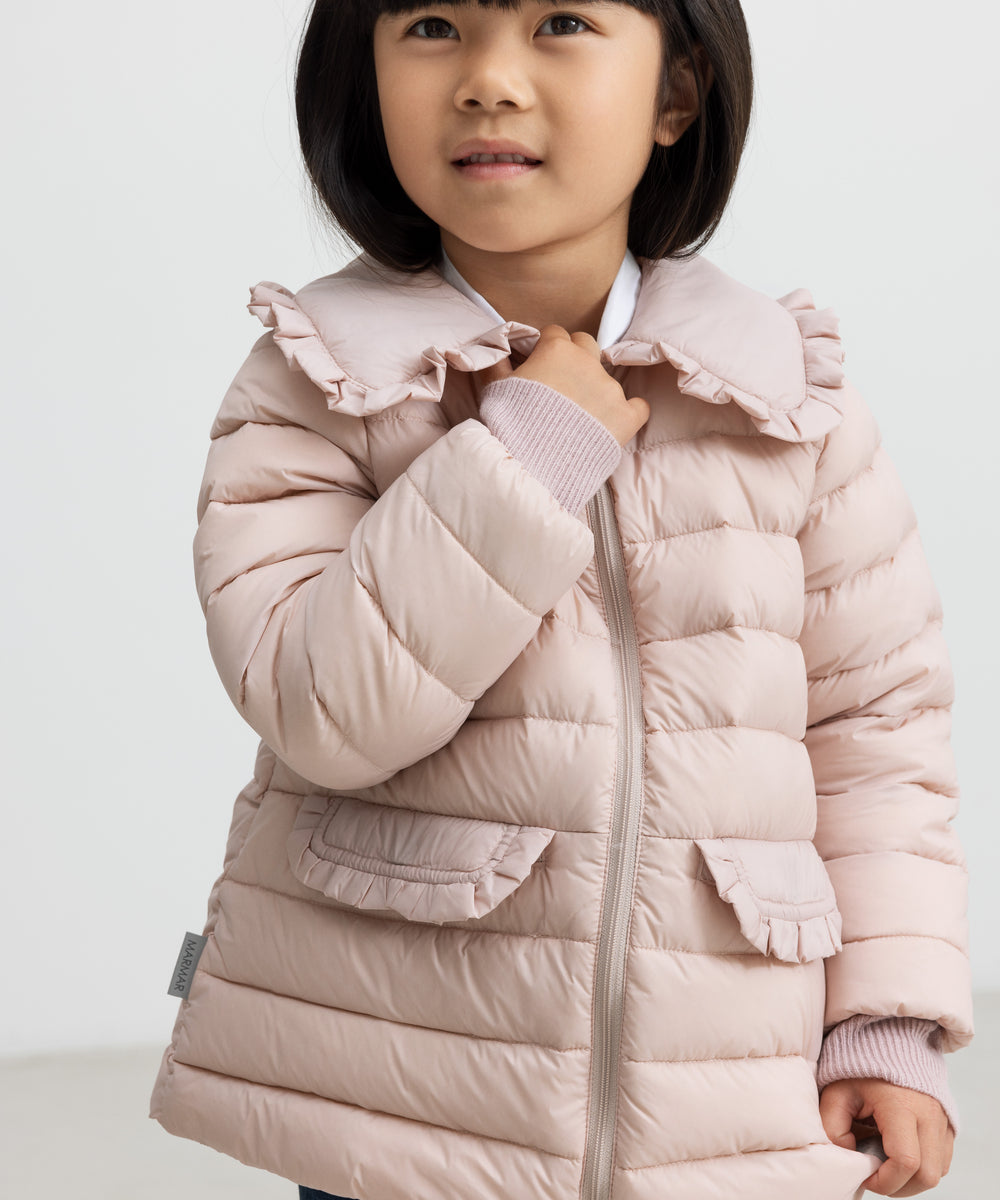 Pige iført lyserød vatteret jakke med flæsekrave