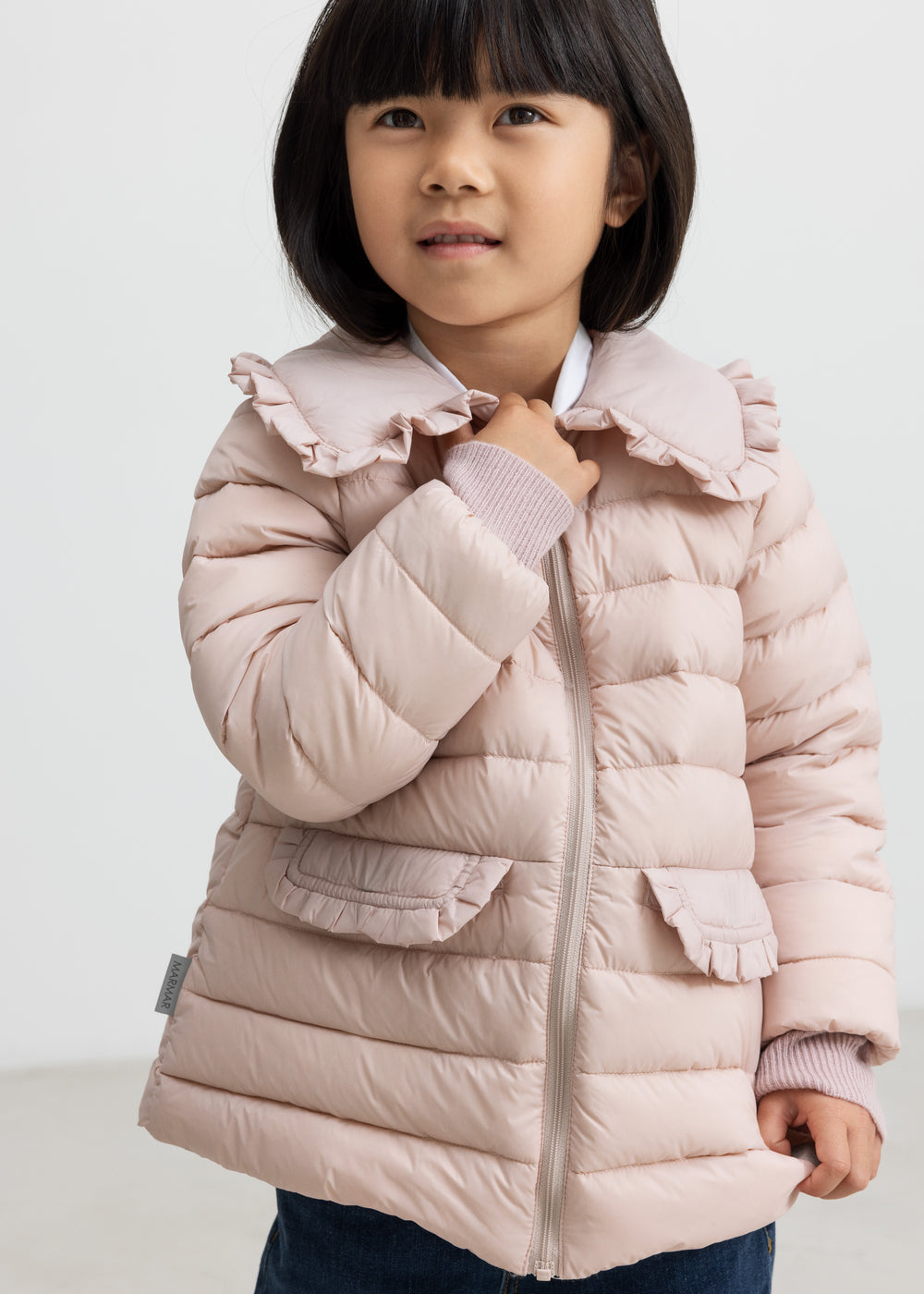 Pige iført lyserød vatteret jakke med flæsekrave